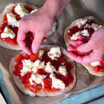 6. Schritt - Tomatenscheiben dann gleichmäßig auf alle Pizzen verteilen.
