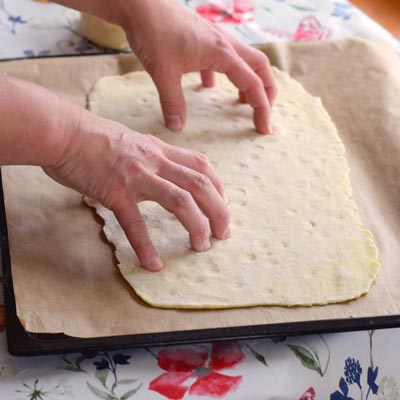 2. Schritt - Vertiefungen im Pizzateig: kleine Vertiefungen werden in den Teig gedrückt