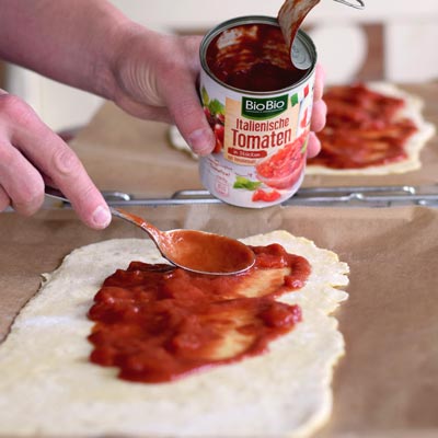 3. Schritt - Dosentomaten auf Pizzateig: sonnengereifte Tomaten aus der Dose werden auf den Teig verteilt