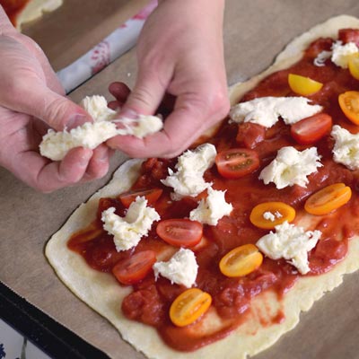 3. Schritt - Mozzarella verteilen: Mozzarella Käse in Stücke auf die Pizza verteilen